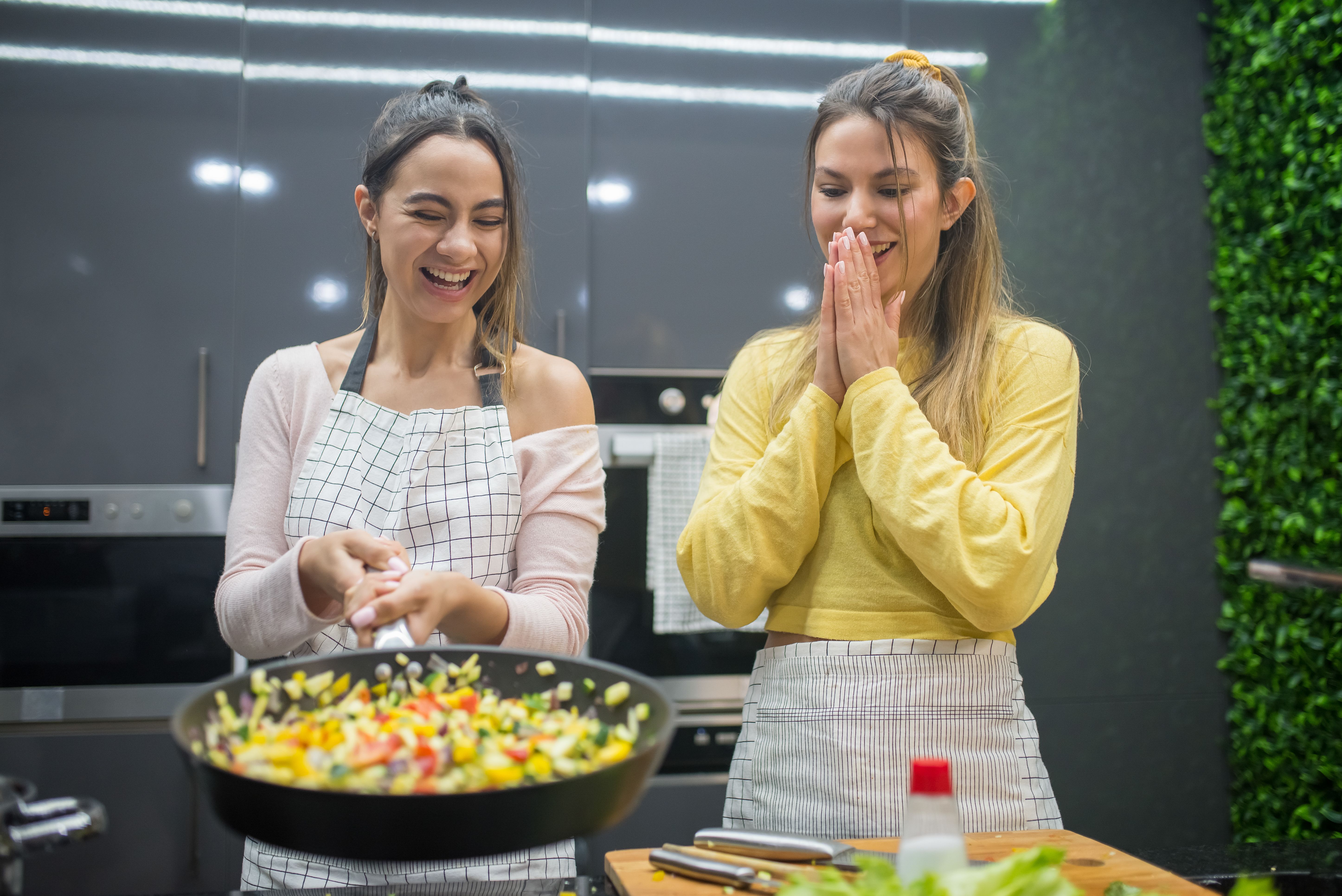 Two friends laughing while cooking